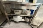 Arbeidsbenk i rustfritt stål med kokekar og kjøkkenutstyr